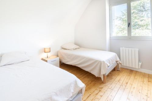 a white bedroom with two beds and a window at Tasmannia - 3 étoiles avec piscine chauffée - Erquy in Erquy