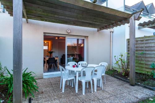 un patio avec une table et des chaises sous une pergola dans l'établissement Le Reflet des Vagues - Proche des plages avec piscine, à Arzon