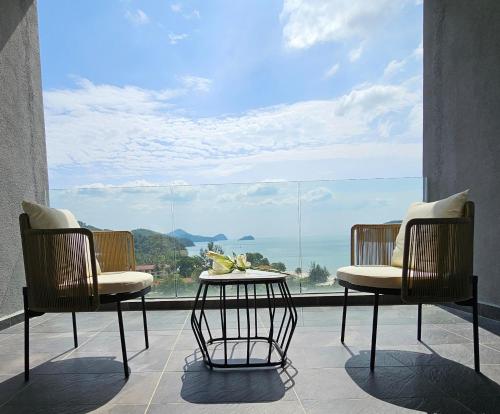 zwei Stühle und ein Tisch vor einem großen Fenster in der Unterkunft The Langkawi Luxury in Pantai Cenang