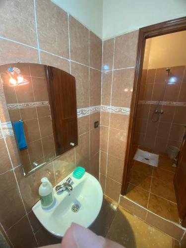 a bathroom with a sink and a shower with a mirror at Adoir N'salh in Tiznit