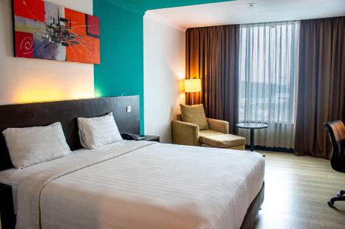 a hotel room with a bed and a chair at King's Hotel Nagoya Batam in Nagoya