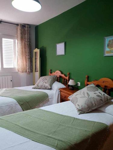 a green room with two beds and a green wall at Apartamento Malecón in Muxia