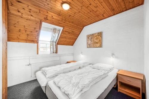 a bedroom with a white bed with a wooden ceiling at Family-Friendly Holiday Home With Pool, Located Close To The North Sea In Vrist in Harboør
