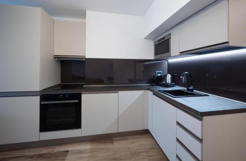 a kitchen with white cabinets and black appliances at Novos Luxury Suites in Bucharest