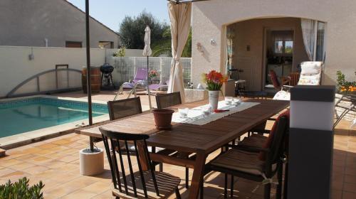 - une table et des chaises en bois à côté de la piscine dans l'établissement Villa spacieuse 8 personnes avec piscine proche des plages, à Vias