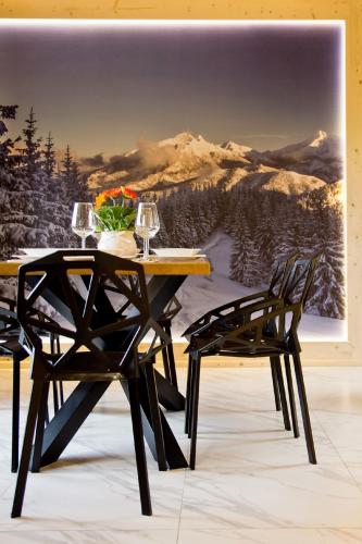 a table and two chairs in front of a painting at Domki GliczarowSKI z Jacuzzi & Sauna in Zakopane