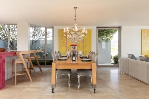 a dining room table with chairs and a chandelier at Benguela Cove - Oceans Away in Hermanus