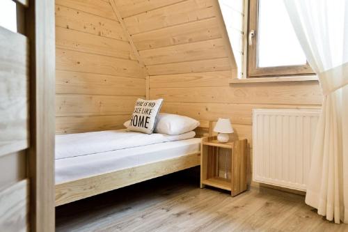 a small bed in a wooden room with a window at Domki GliczarowSKI z Jacuzzi & Sauna in Zakopane