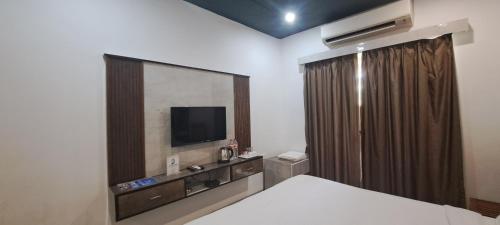 a bedroom with a bed with a tv and a mirror at Sia Signature Calangute in Calangute