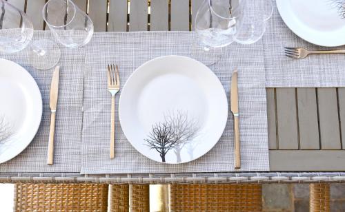 a table with white plates and a tree on it at Vourkari, modern apartment overlooking the Marina of Vourkari in Vourkarion
