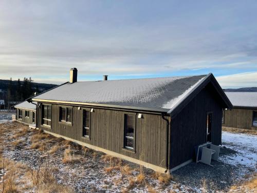a black building with a tin roof on a field at Hjertebo by Norgesbooking - cabin at Spåtind in Nord Torpa