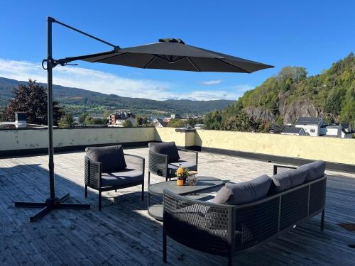 a patio with chairs and an umbrella on a roof at Stor innbydende leilighet med 4 soverom og sentral beliggenhet in Notodden