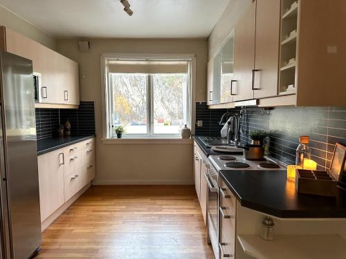 a kitchen with white cabinets and a large window at Stor innbydende leilighet med 4 soverom og sentral beliggenhet in Notodden