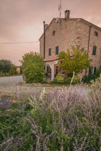an old stone building with flowers in front of it at B&B il mio Casale in Colà di Lazise