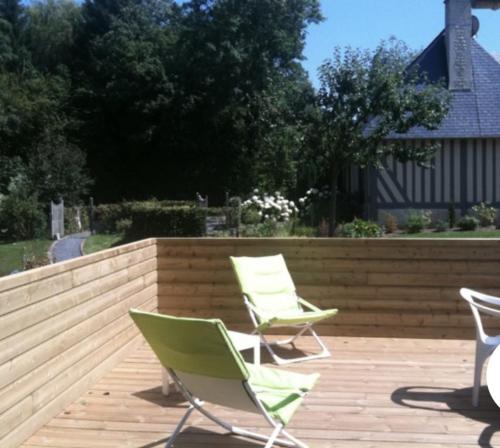 2 sedie verdi sedute su una terrazza di legno di Les Brunières a Tourville-en-Auge