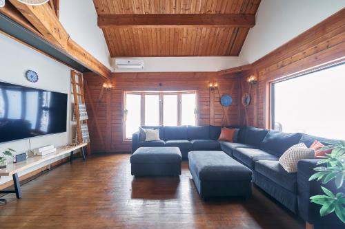 a living room with a blue couch and a flat screen tv at Mominoki Lodgeモミの木ロッジ in Minakami