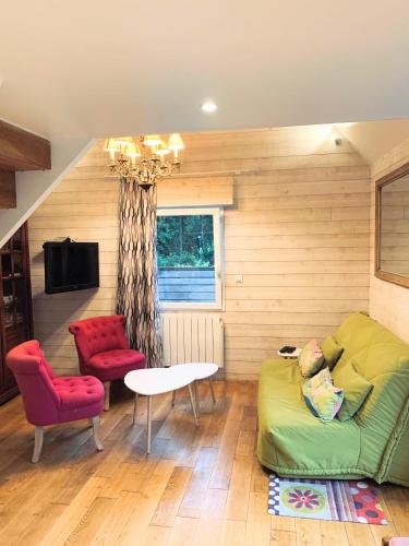 - un salon avec un canapé vert et 2 fauteuils rouges dans l'établissement Les Brunières, à Tourville-en-Auge