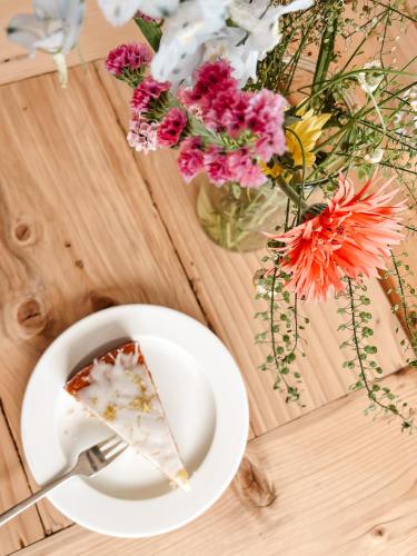 a piece of cake on a table with a cup and flowers at Ostsee-Strandhaus-Holnis in Glücksburg