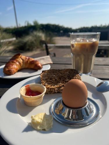 a plate of food with eggs and bread and a drink at Ostsee-Strandhaus-Holnis in Glücksburg