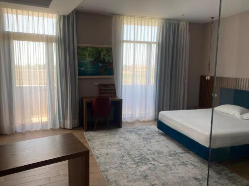 a bedroom with a bed and a desk and windows at Hotel Vila Aleksander 1 in Shijak