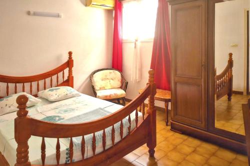 a bedroom with a wooden bed and a chair at Appartement confortable avec vue sur la mer à Fort-de-France - 44 m² in Fort-de-France