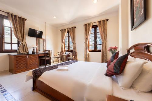 a bedroom with a bed and a desk and windows at Hùng Phong Hotel - Near Dalat Market in Da Lat
