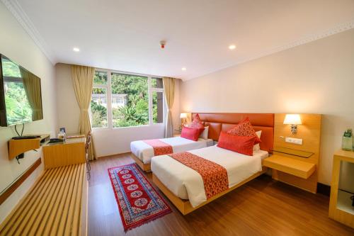 een hotelkamer met twee bedden en een televisie bij Sinclairs Gangtok in Gangtok