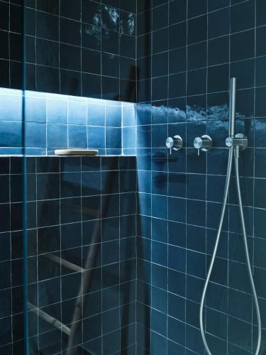 a blue tiled bathroom with a shower with a hose at Sirene Blue Luxury Beach Resort in Poros