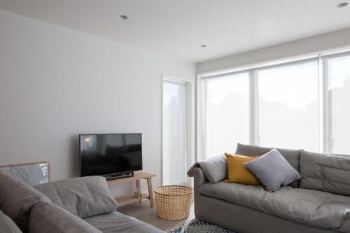 a living room with a couch and a flat screen tv at Insta-worthy 4br designer house 5 min to the beach in West Wittering