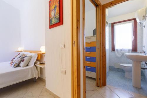 een slaapkamer met een bed, een wastafel en een toilet bij Villa Mama con piscina condominiale, giardino e barbecue in SantʼAnna Arresi