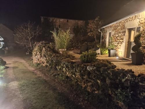 a stone wall in front of a house at night at Lili de La LisaThi in Cruéjouls