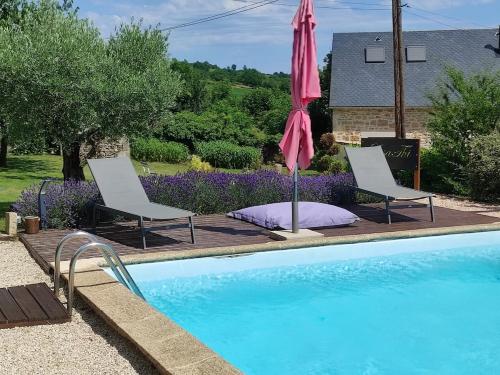 two chairs and an umbrella next to a swimming pool at Lili de La LisaThi in Cruéjouls