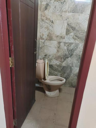 a bathroom with a toilet and a stone wall at Hotel Hill Town Coorg in Madikeri