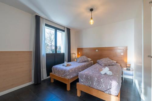 ein Schlafzimmer mit zwei Betten und einem Fenster in der Unterkunft Les Coteaux 4 - Avec jardin à Argenteuil in Argenteuil