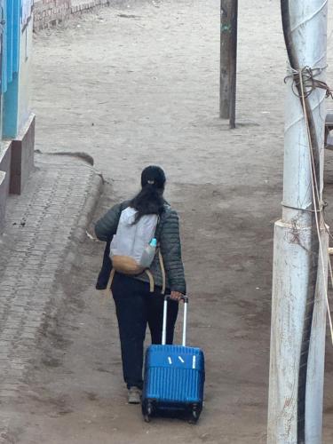 a woman walking down a street with a blue suitcase at SEO House in Aswan