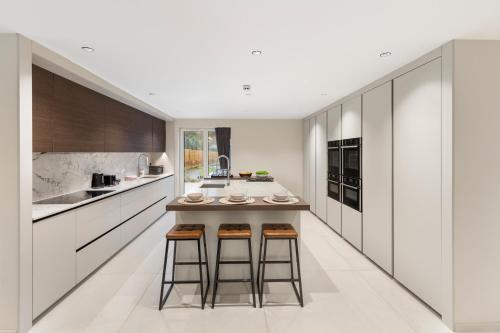 a kitchen with white cabinets and bar stools at Joy Lane Mansion, Luxe Stay, Poolside Fun & Comfort in Kent