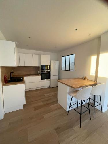 une cuisine avec des armoires blanches et une table et des chaises en bois dans l'établissement Maison neuve mer, plage, gr 34 à pieds, à Assérac