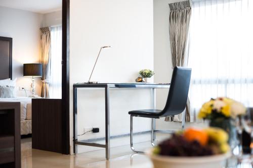 a room with a chair and a desk and a bed at Beyond Suite in Bangkok