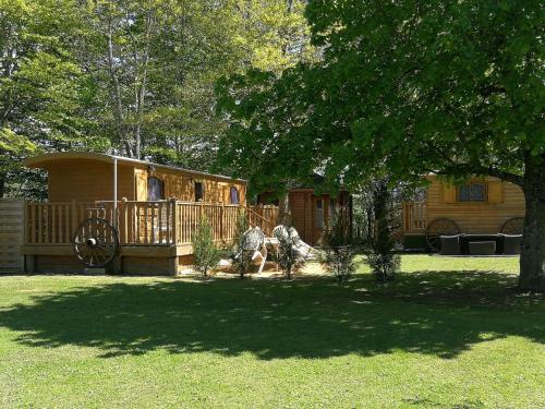 a cabin in a yard with a horse pulling a cart at La Roulotte du Parc in Saint-Priest-des-Champs