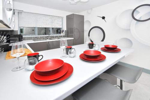 a kitchen with red plates and glasses on a counter at Townhouse @ Aboyne Close Birmingham in Birmingham
