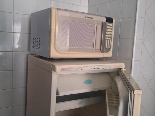 a microwave sitting on top of a machine at Apartamento no Centro in Poços de Caldas