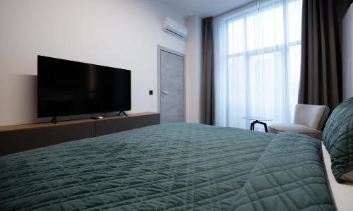 a hotel room with a bed and a flat screen tv at Novos Luxury Suites in Bucharest