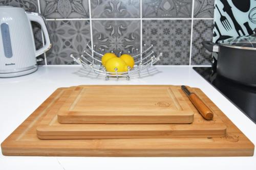a wooden cutting board on a counter with a basket of lemons at Townhouse @ Aboyne Close Birmingham in Birmingham