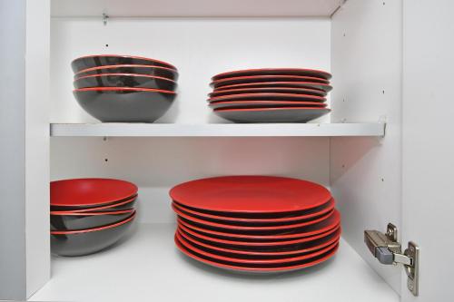 a shelf with red and black bowls and plates at Townhouse @ Aboyne Close Birmingham in Birmingham
