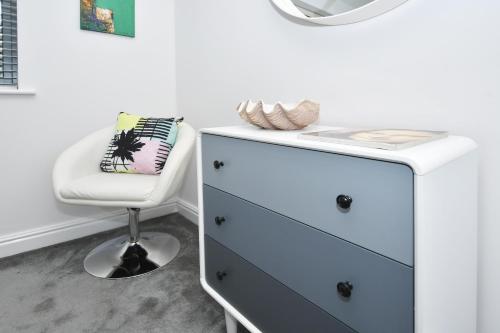 a white dresser and a chair in a room at Townhouse @ Aboyne Close Birmingham in Birmingham