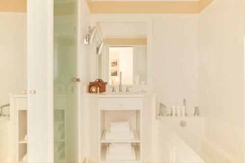 un bagno bianco con lavandino e specchio di Hôtel Barrière L'Hermitage a La Baule