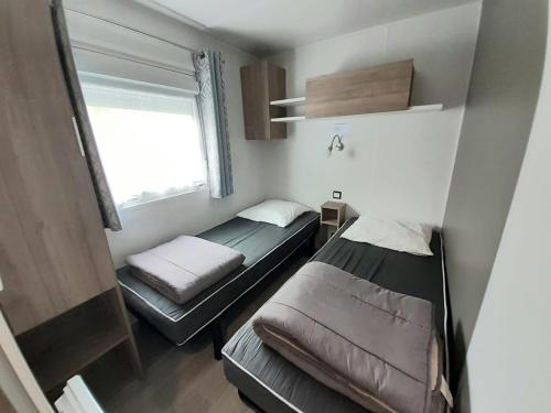 une petite chambre avec deux lits et une fenêtre dans l'établissement Mobilhome Le Serenité - La Plage, à Mimizan-Plage