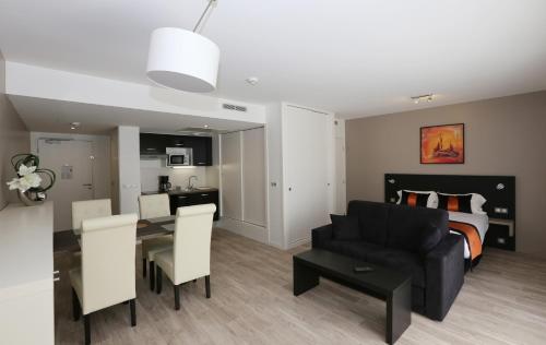 - un salon avec un canapé noir et un lit dans l'établissement La Résidence 126, Appart'Hôtel, à Blanquefort