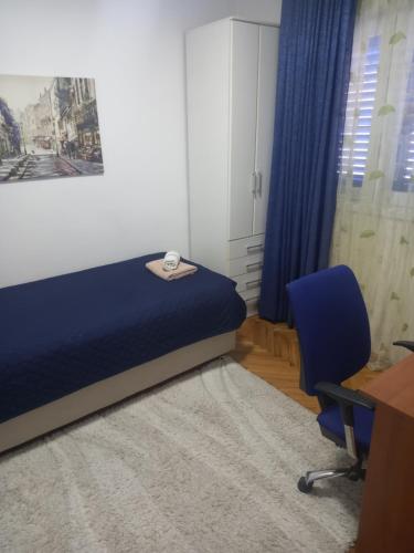 a bedroom with a blue bed and a desk and a chair at Stan u maslinama in Podgorica