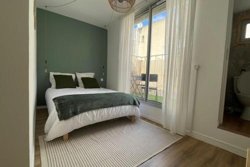 une chambre avec un lit aux murs verts et une fenêtre dans l'établissement L'Aycelin - Appartement proche des Halles Wifi, à Narbonne